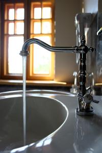 a sink with a faucet with water coming out at Klasztor Cedynia Hotel in Cedynia
