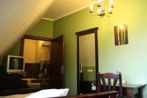 ein Schlafzimmer mit grünen Wänden, einem Bett und einem Spiegel in der Unterkunft Klasztor Cedynia Hotel in Cedynia