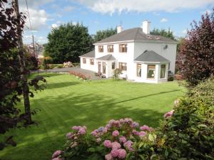 uma casa branca com um jardim verde com flores em Millhouse B&B em Ballymote