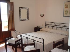 a bedroom with a bed and two chairs and a mirror at Antica Gebbia in Siracusa