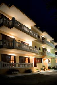 Un grand bâtiment blanc avec balcon est disponible la nuit. dans l'établissement Hotel Kastri, à Loutra Edipsou