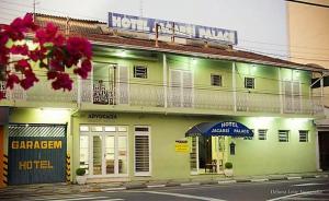 a green building with an umbrella on a street at Hotel Jacarei Palace in Jacareí