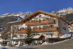 a large hotel building in the mountains with snow at Hotel Cristallo in Vigo di Fassa