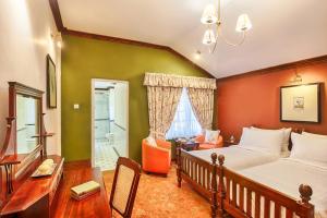 a bedroom with a bed and a desk and a chair at Oatlands by Jetwing in Nuwara Eliya