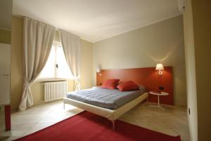a bedroom with a bed with red walls and a window at Relais Corte Bergamini in Peschiera del Garda