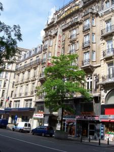 un alto edificio con un albero di fronte a una strada di Hotel Manhattan a Bruxelles