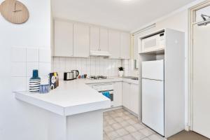 a kitchen with white cabinets and a white refrigerator at South Perth Executive Apartment in Perth