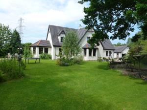 a house with a green yard in front of it at Home Farm Bed and Breakfast in Muir of Ord