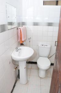 a white bathroom with a toilet and a sink at Safari Inn in Dar es Salaam