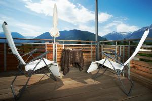 two chairs and an umbrella on a deck with mountains at Hotel Ladurner in Merano