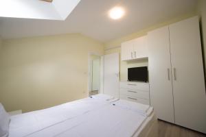 ティミショアラにあるGaga Residence 14の白いベッドルーム(ベッド2台、テレビ付)