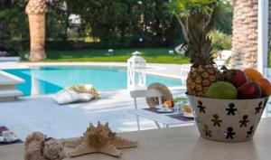 a bowl of fruit on a table next to a pool at Villa Vulcano in Marina di Ragusa