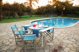 a table and chairs next to a swimming pool at Ibiscus Hotel Malia in Malia