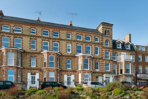 a large brick building with cars parked in front of it at 2 Bed beach front apartment with spectacular views overlooking Viking Bay in Broadstairs