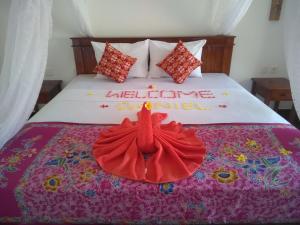 a bed with a red dress on top of it at Krisna Homestay in Pemuteran