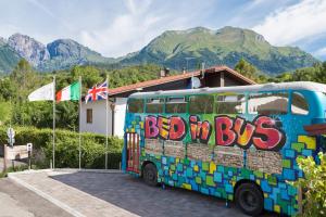 um autocarro estacionado em frente a um edifício com bandeiras em Bed In Bus em Belluno