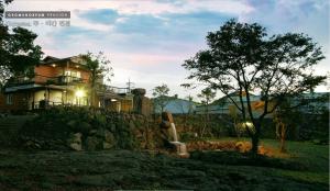 a house sitting on top of a stone wall at Gotjawal Geomunoreum Pension in Jeju