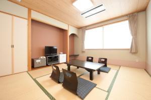 een eetkamer met een tafel en stoelen en een televisie bij Kur and Hotel Suruga in Shizuoka