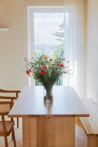 un jarrón de flores sentado en una mesa frente a una ventana en Landhaus 3 Birken, en Landkern