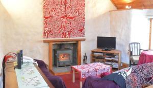 a living room with a fireplace and a tv at Glas Bheinn Cottage in Luib