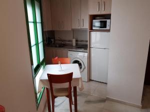 a small kitchen with a table and a white refrigerator at Fan Flat Rosaleda in Málaga