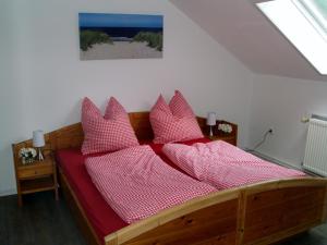 a bed with red sheets and pink pillows at Schleusenhof Ferienwohnung in Spieka-Neufeld +34 photos