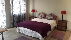 een slaapkamer met een bed met paarse lakens en kussens bij Khaya la Manzi in Port Edward