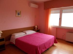 um quarto com uma cama rosa e uma janela em Hotel Maremonti em Vico del Gargano