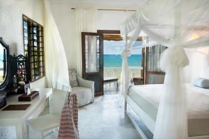 a bedroom with a bed and a view of the ocean at Chuini Zanzibar Lodge by NEWMARK in Zanzibar City