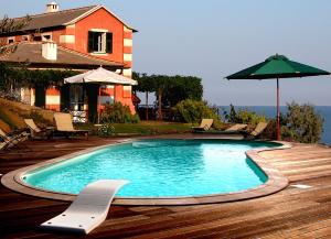 a swimming pool with chairs and an umbrella and a house at Agriturismo Natta Di Monte Tabor in Celle Ligure
