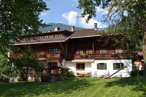 ein großes Holzhaus mit Rasen davor in der Unterkunft Böglhof in Stumm