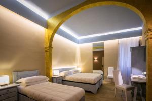 a hotel room with two beds and a table and a desk at Bed and Breakfast Mameli 67 in Montefalco