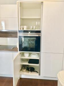 a white kitchen with white cabinets and appliances at 2-Bedrooms Modern Apartment next to Velodrome, Lounge, Balcony, Parking, ABBA in London
