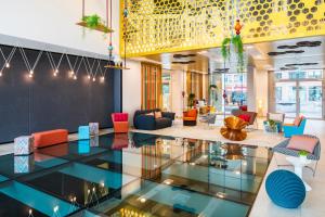 een lobby met kleurrijke stoelen en een glazen vloer bij Capri by Fraser Berlin in Berlijn