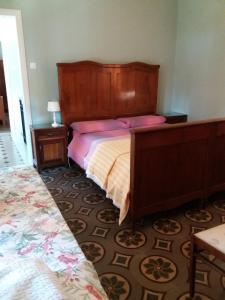 a bedroom with a bed with a wooden headboard and pink pillows at IL PRINCIPINO B&B in Massa