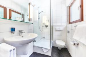 a white bathroom with a sink and a toilet at Waldhotel Sulzbachtal in Schönaich