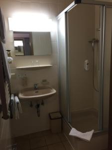 a bathroom with a sink and a shower with a glass door at Hotel Kelkheimer Hof in Kelkheim