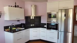 a kitchen with white cabinets and a stainless steel refrigerator at Casa Rural Oscar in Baiona