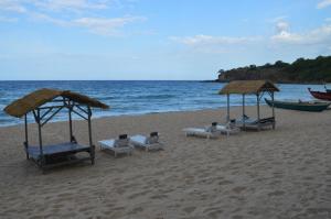 a group of chairs and umbrellas on a beach at Dutch Bay Beach Cottages in Trincomalee