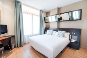 バレンシアにあるPetit Palace Ruzafaのベッドルーム(大きな白いベッド1台、テレビ付)