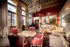 un soggiorno con lampadario pendente, tavolo e sedie di Ruzzini Palace Hotel a Venezia