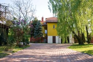a brick road in front of a yellow house at Apisoltysowka in Powązki