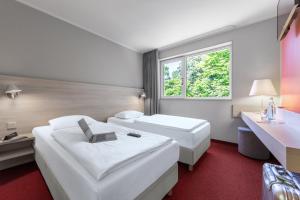 a hotel room with two beds and a window at Serways Hotel Bruchsal West in Forst