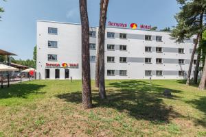 a white building with a tree in front of it at Serways Hotel Bruchsal West in Forst