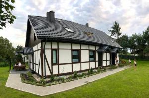 a house with a black roof on a green field at A Morze Ustka in Ustka