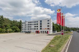 ein Gebäude mit zwei roten Flaggen davor in der Unterkunft Serways Hotel Weiskirchen Nord in Rodgau