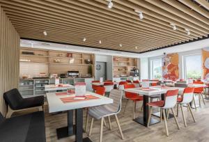 a restaurant with white tables and red chairs at Serways Hotel Weiskirchen Nord in Rodgau