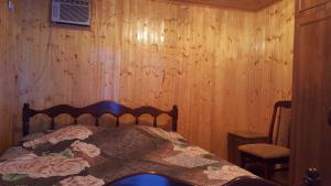 sypialnia z łóżkiem i drewnianą ścianą w obiekcie Частный сектор w mieście Suchumi