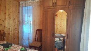 a bedroom with two beds and a chair and a mirror at Частный сектор in Sukhum
