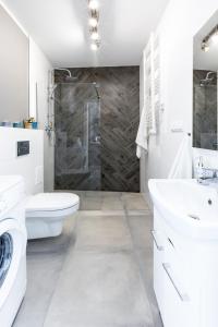 a white bathroom with a shower and a toilet and a sink at Friendhouse Apartments Avenue in Krakow